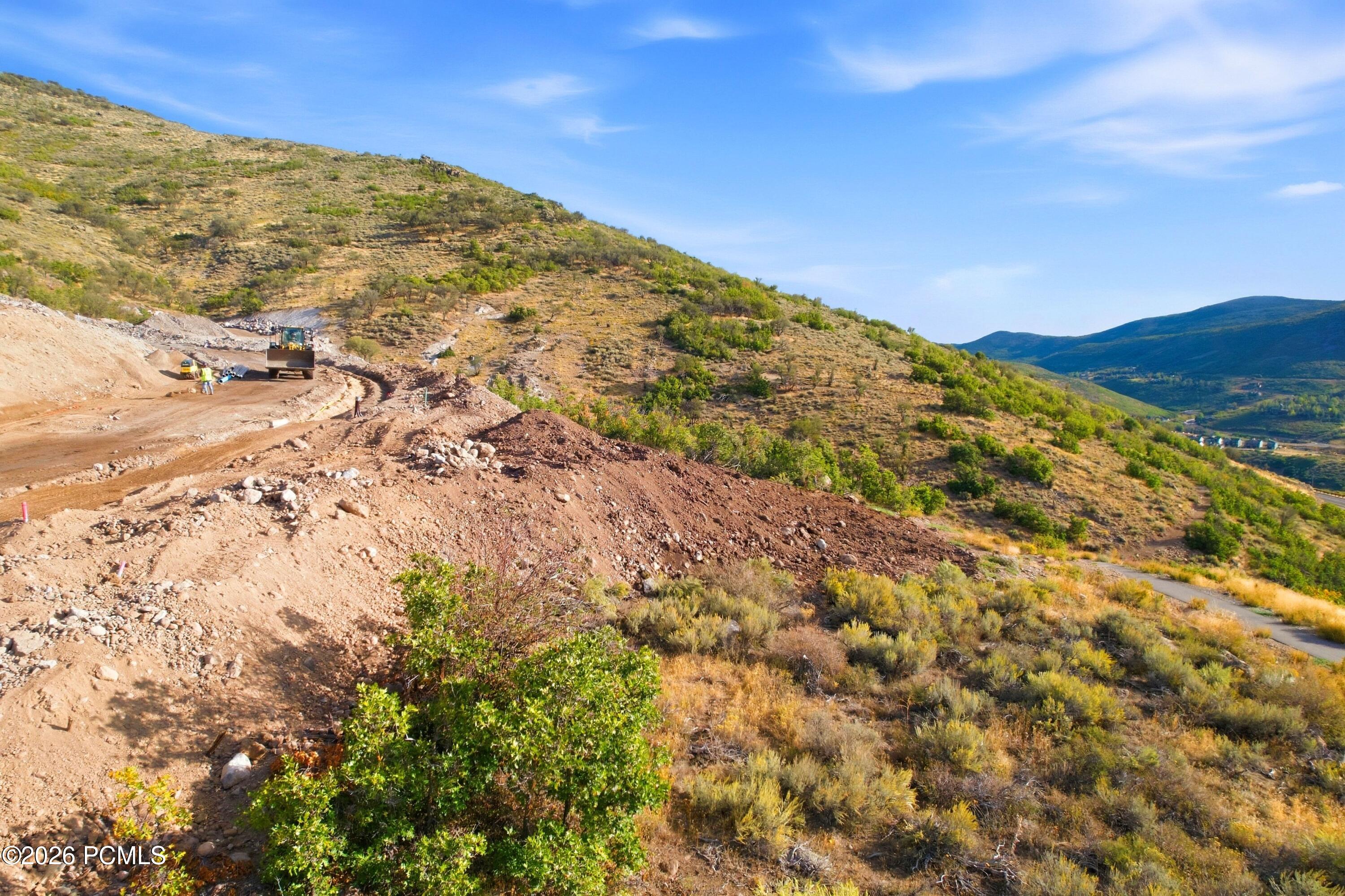 Hillside property under grading, with construction equipment and mountain valley views.