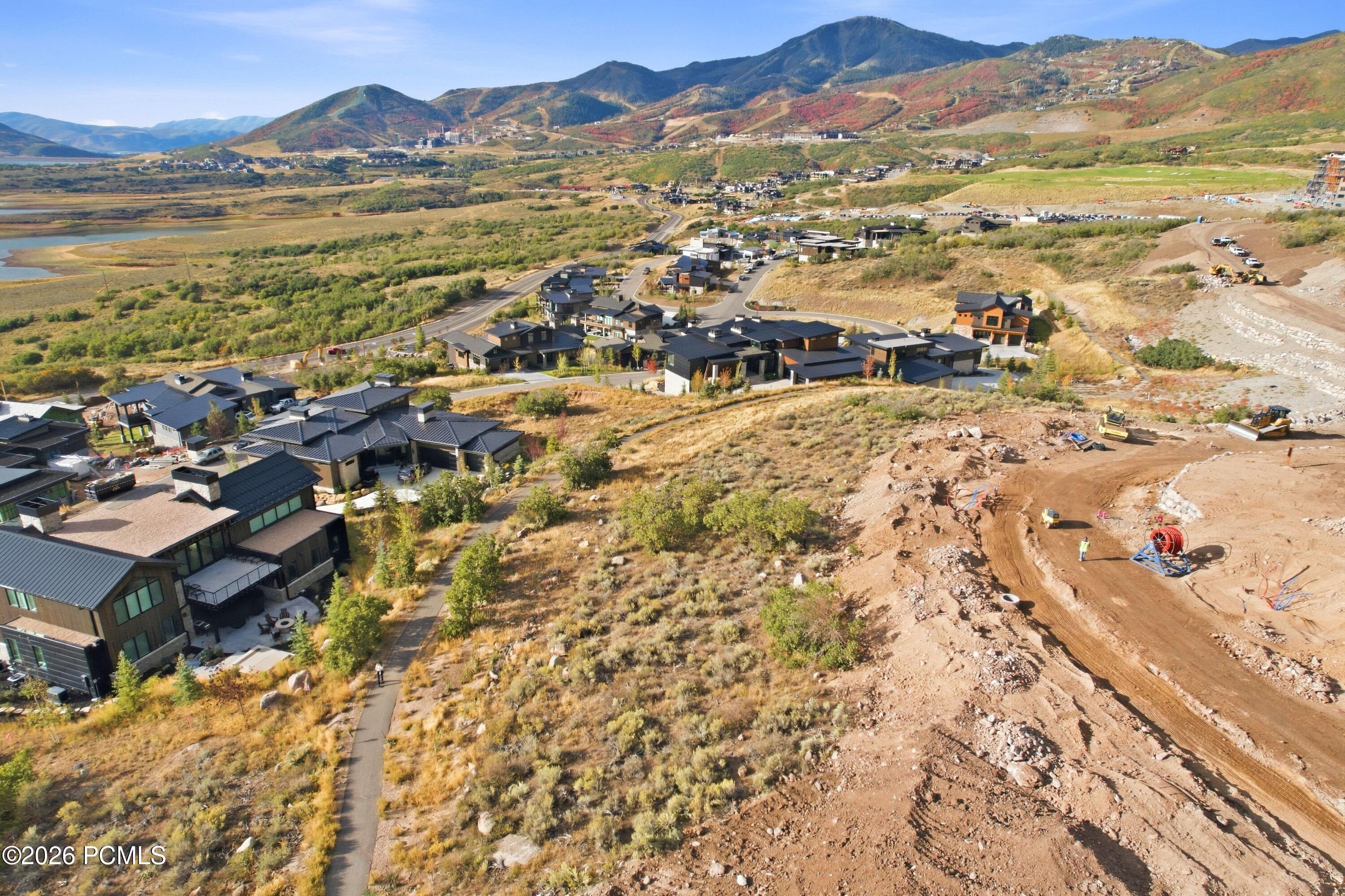 Aerial view of modern homes and active construction below autumn-colored mountains.