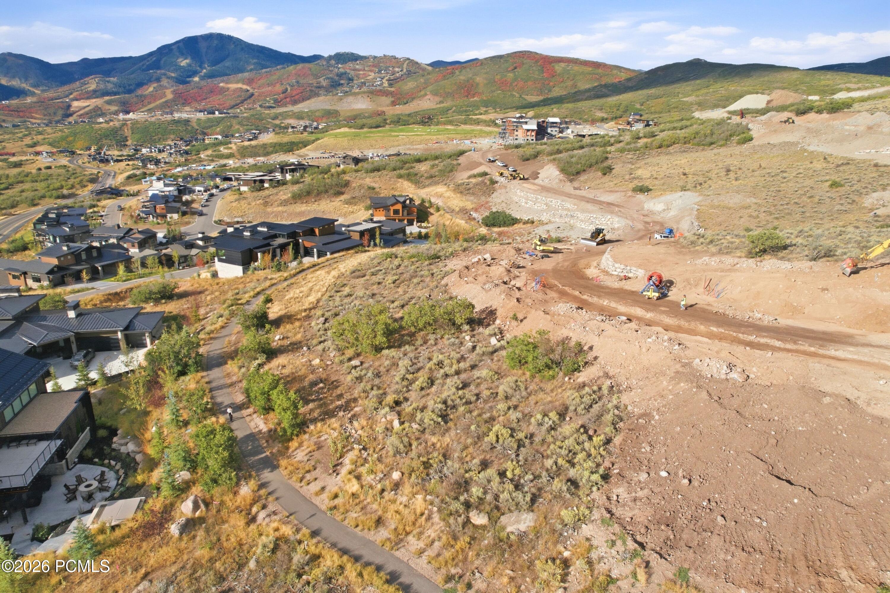 Aerial view of hillside homes and active construction, with autumn-colored mountains beyond.