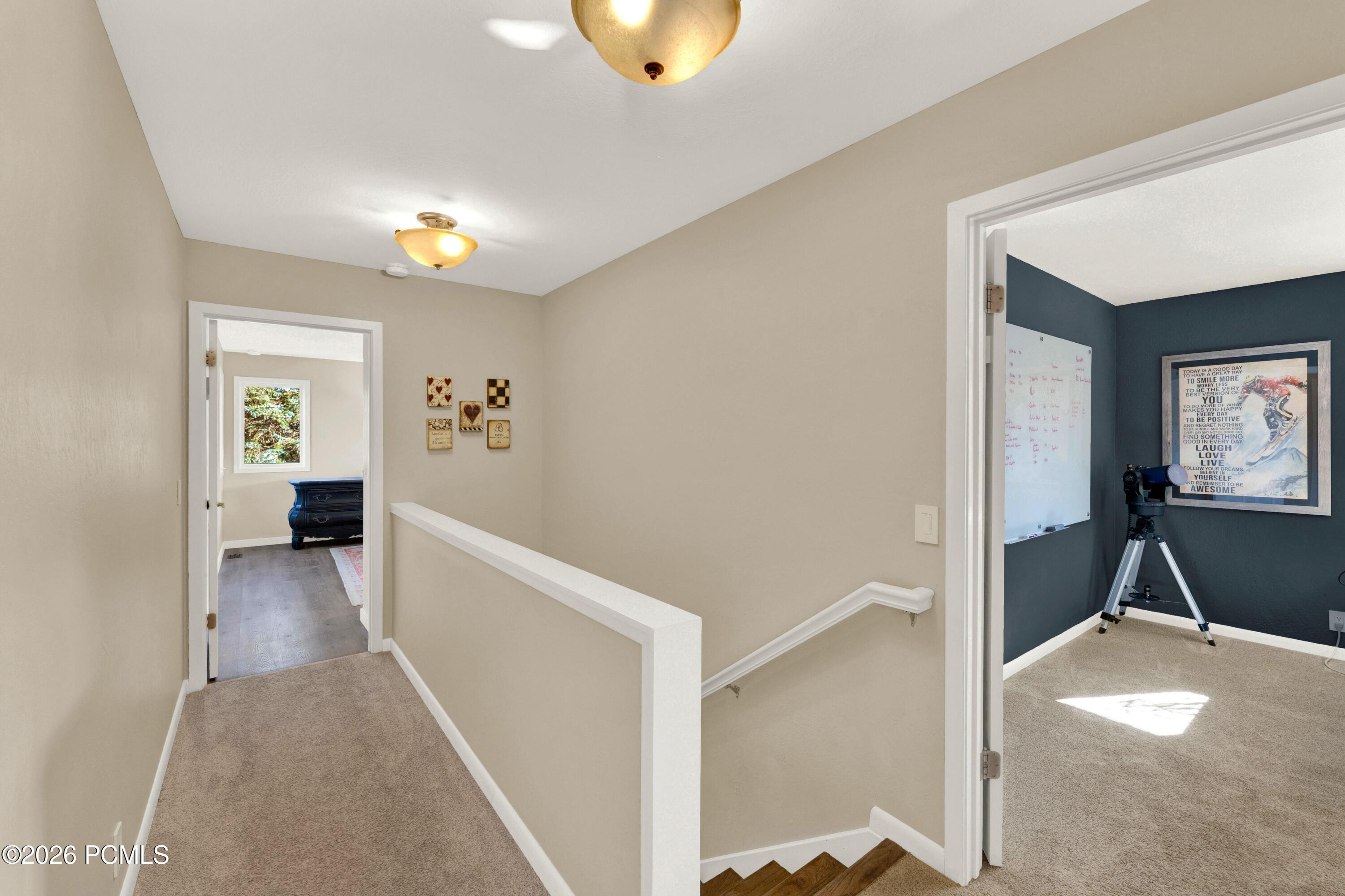 Upstairs hallway and stair landing with a white railing, opening onto a blue office with a telescope.