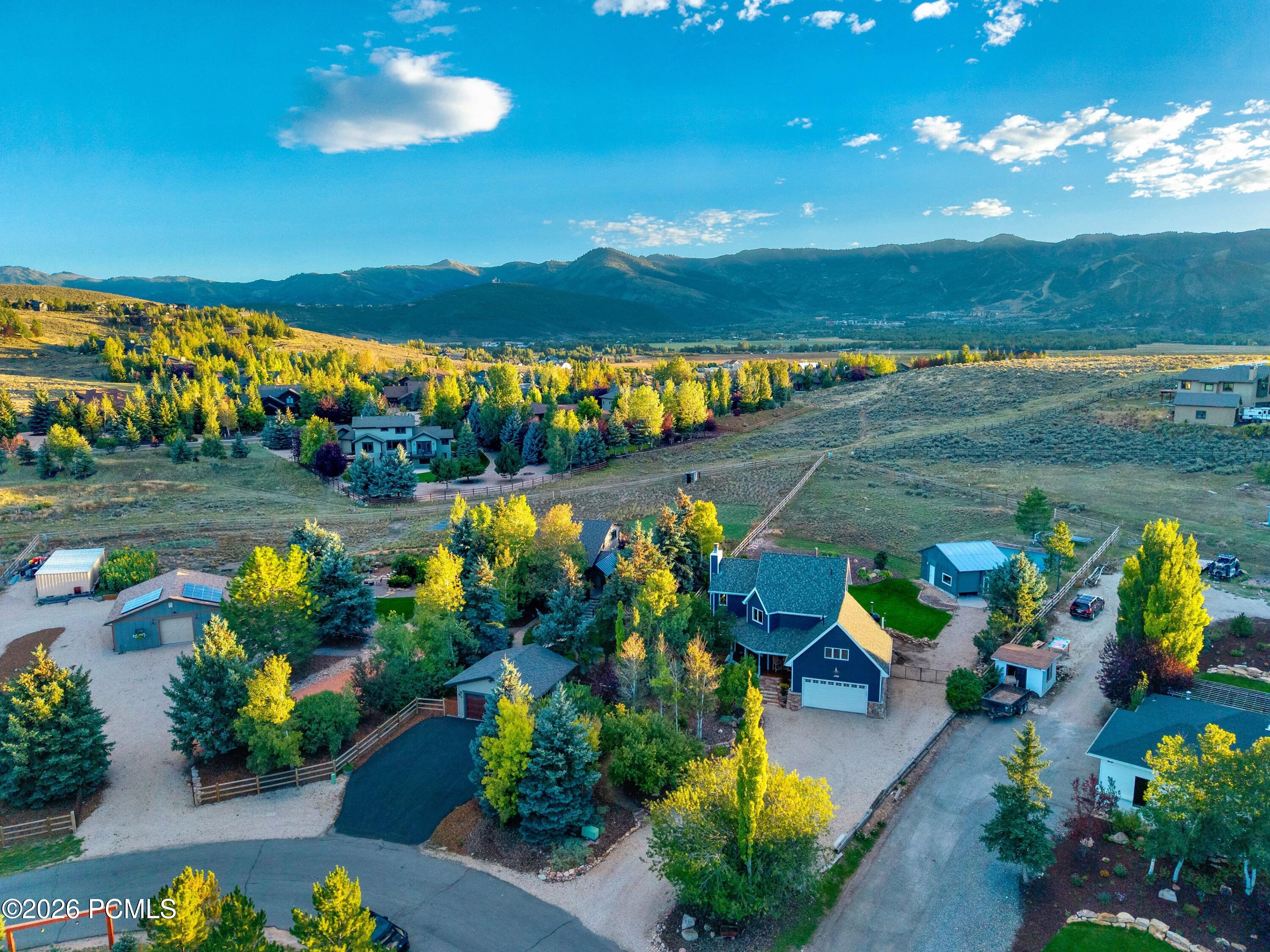 Aerial view of a two-story home on a spacious lot, with autumn trees and mountains in the background.