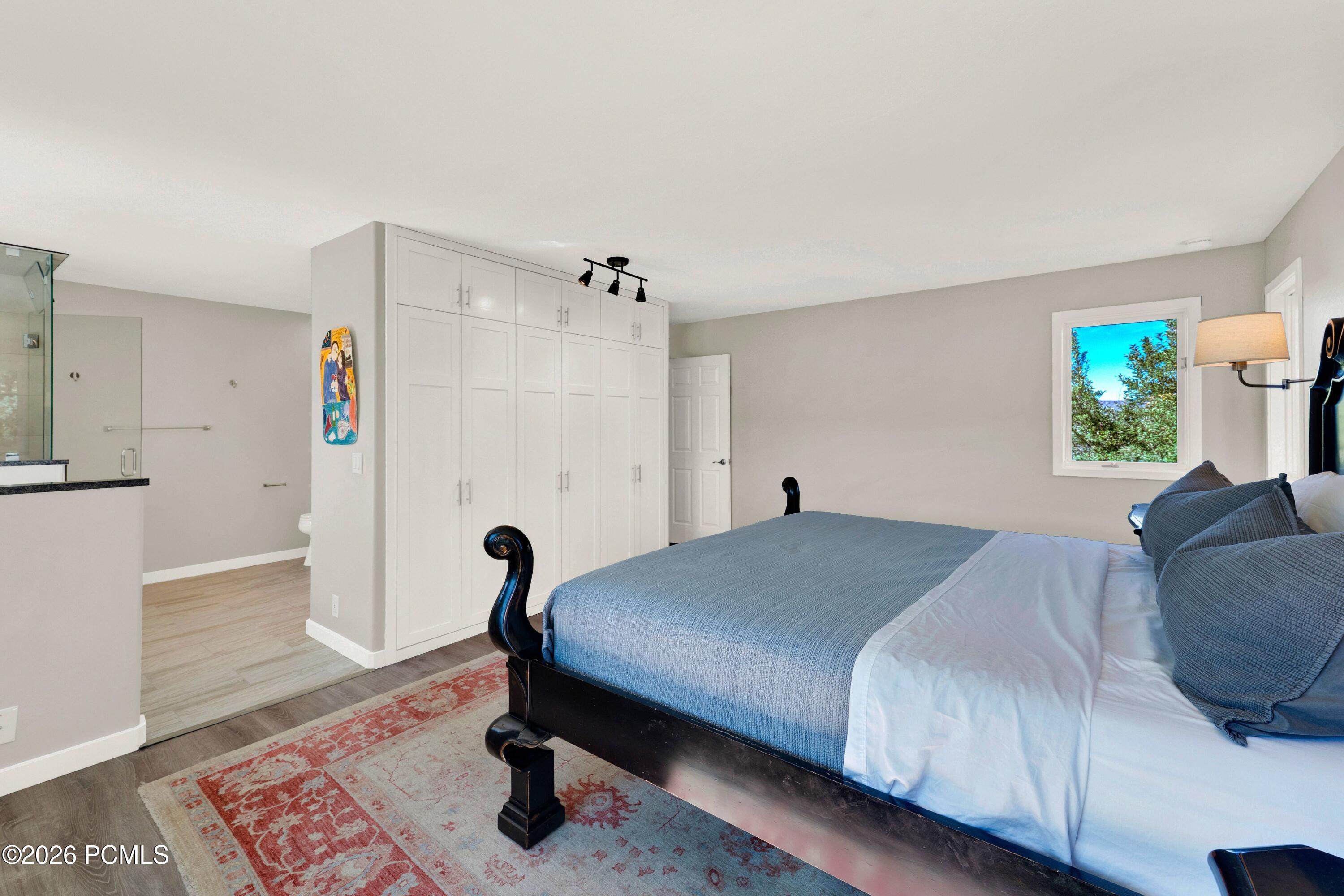 Bedroom with a blue-covered bed, white built-in closets, and an attached bathroom.
