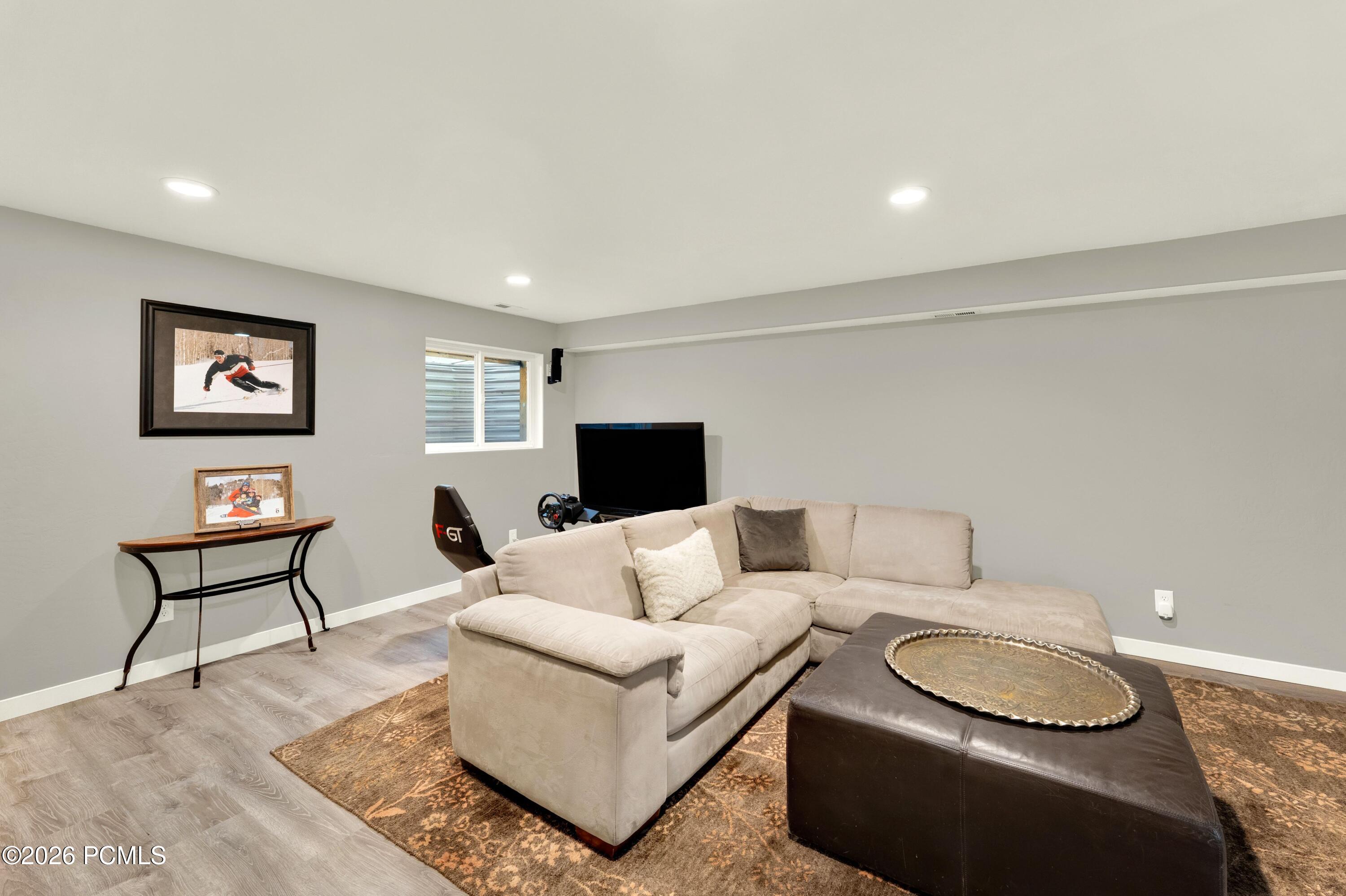 Family room with a beige sectional, television, and racing simulator setup.