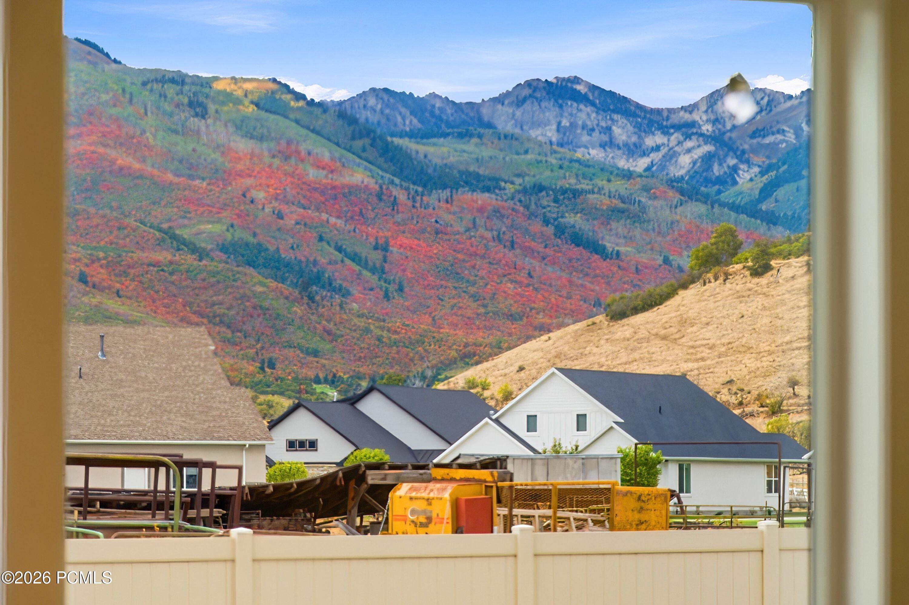 Autumn mountain view beyond neighboring homes, framed by a window.