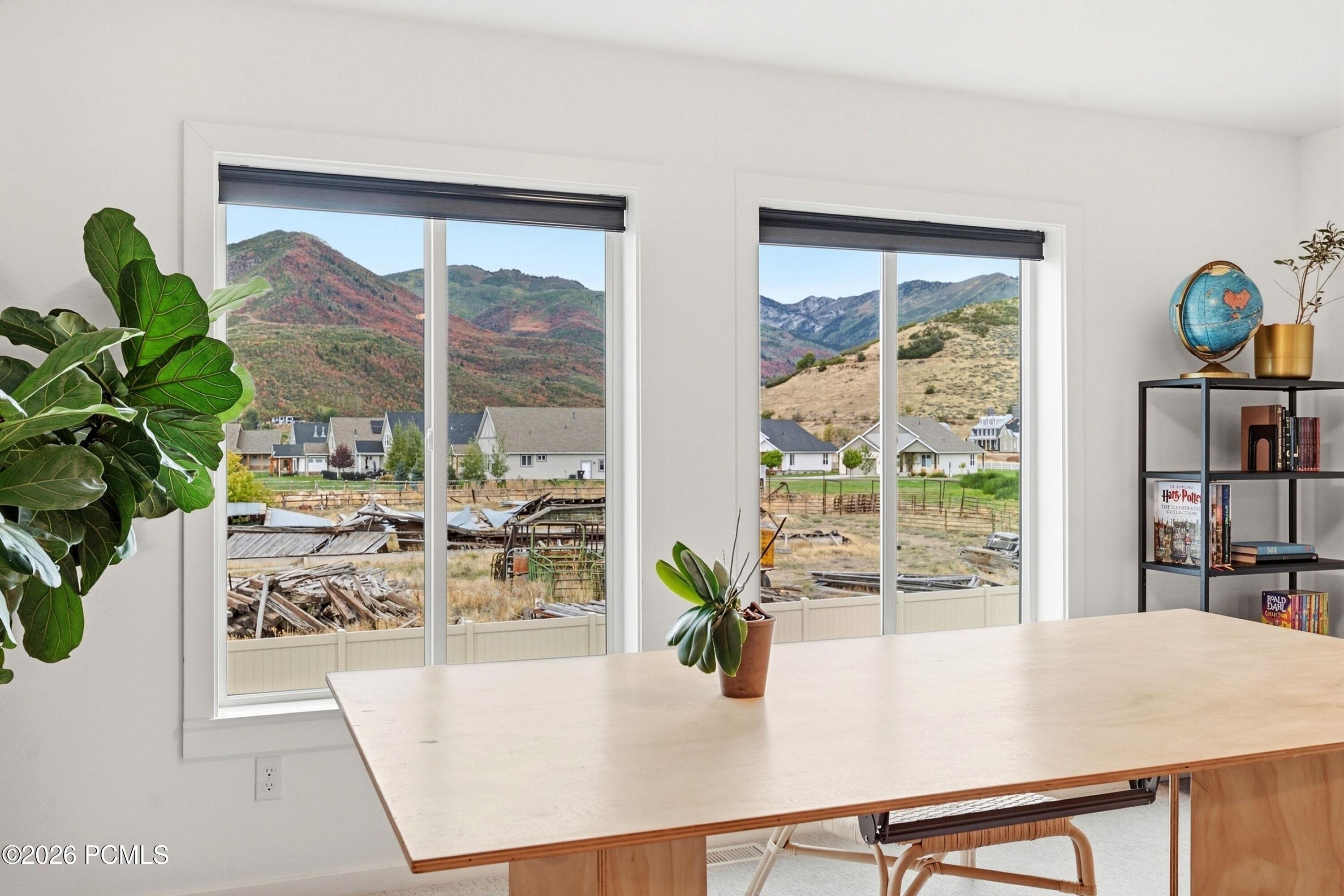 Bright workspace with a large table and mountain views through two tall windows.