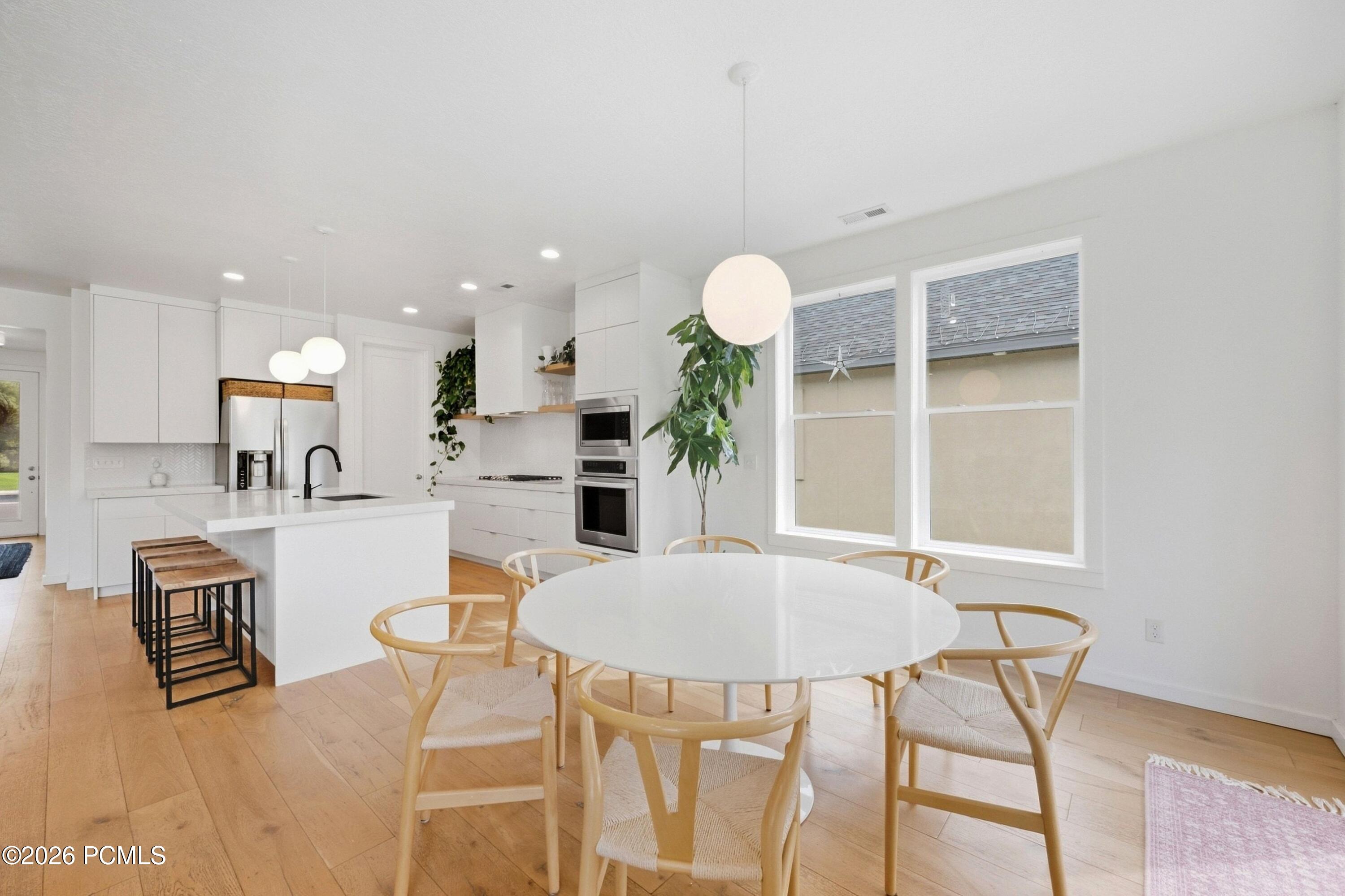Open-plan kitchen and dining area with a white island, round table, and light wood floors.