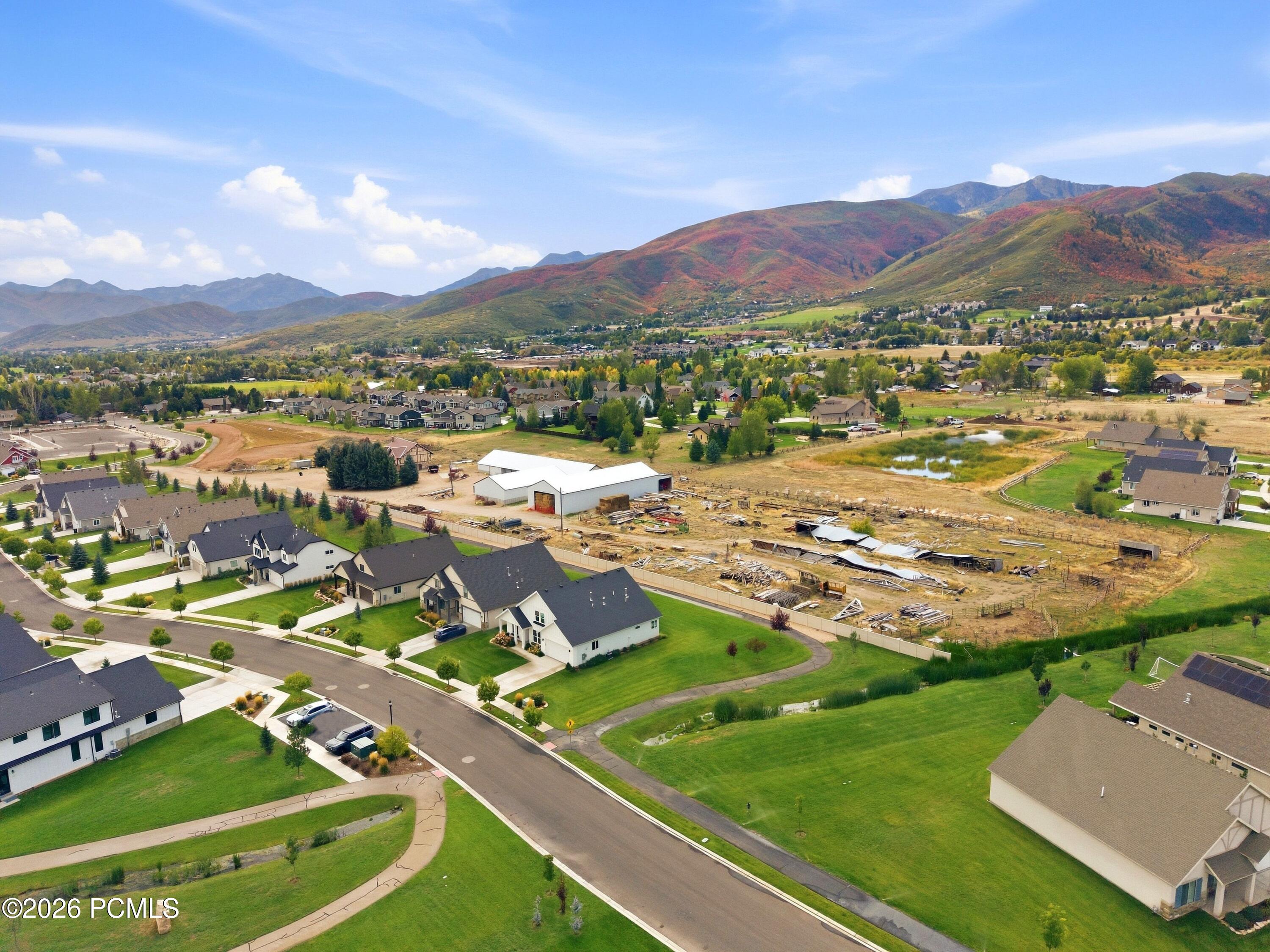 Aerial view of homes, a construction site, and autumn-colored mountains beyond.