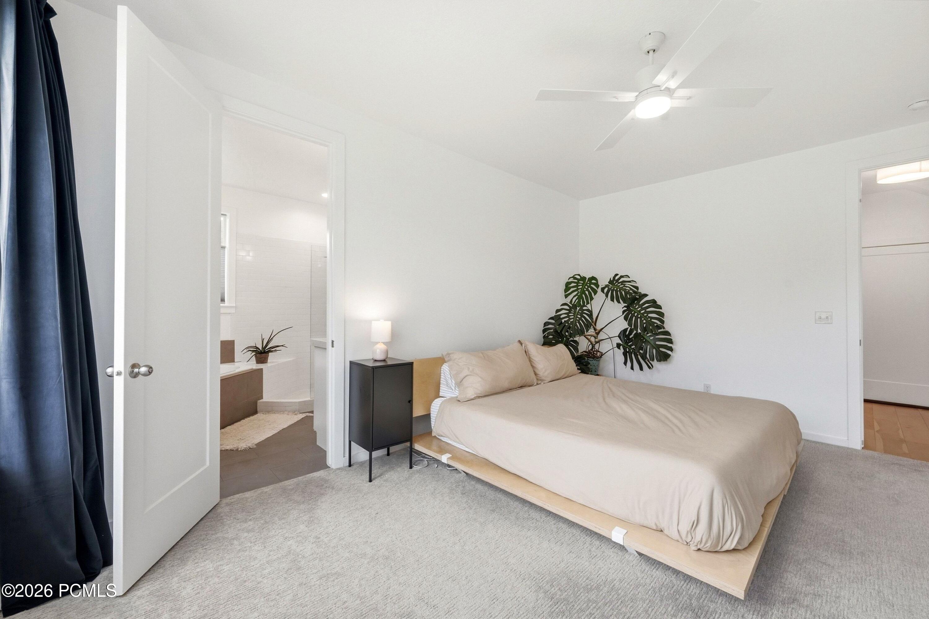 Bedroom with a low platform bed, neutral bedding, and a doorway to the adjoining bathroom.