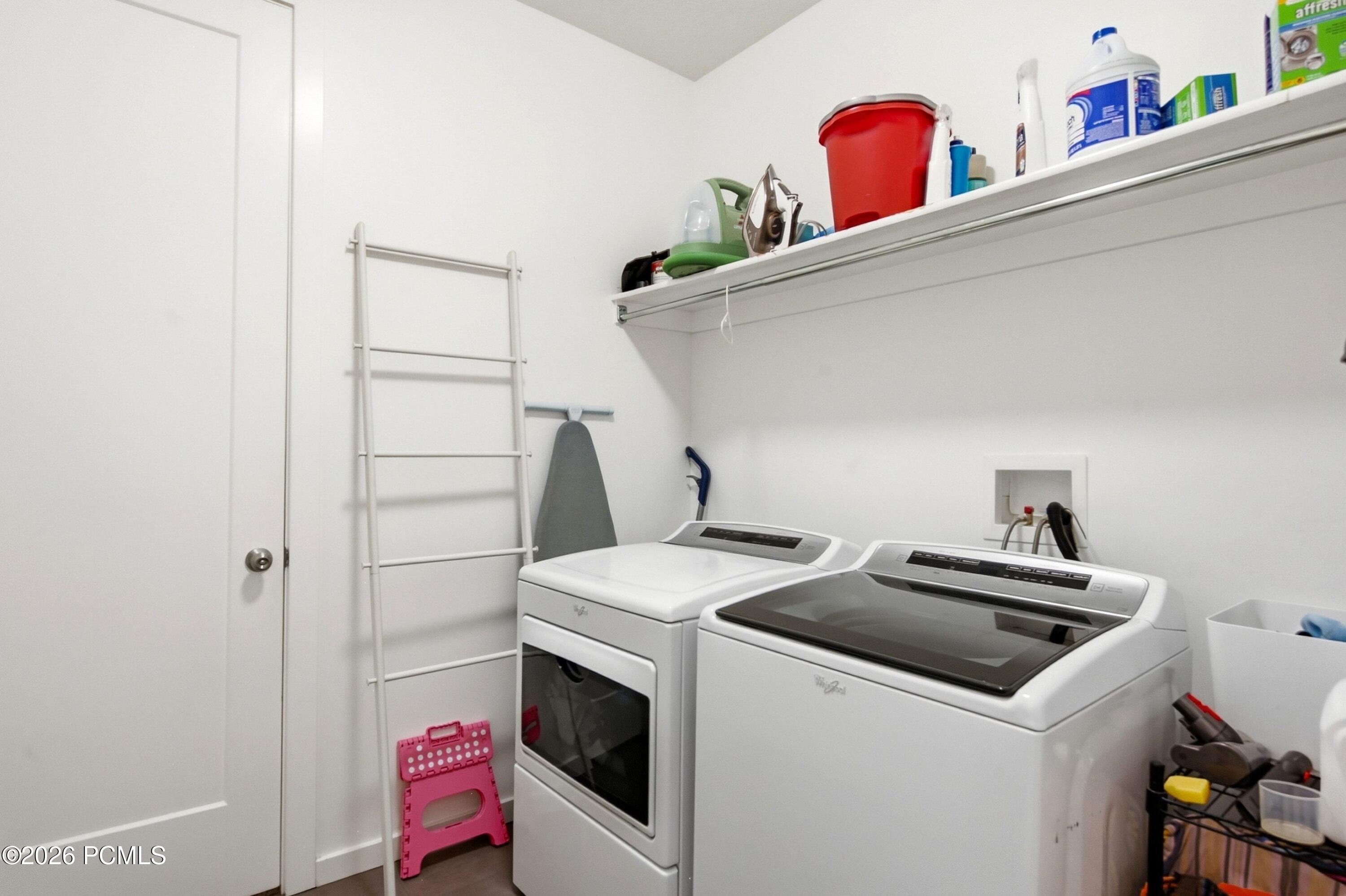 Laundry room with a washer and dryer beneath a shelf of cleaning supplies.