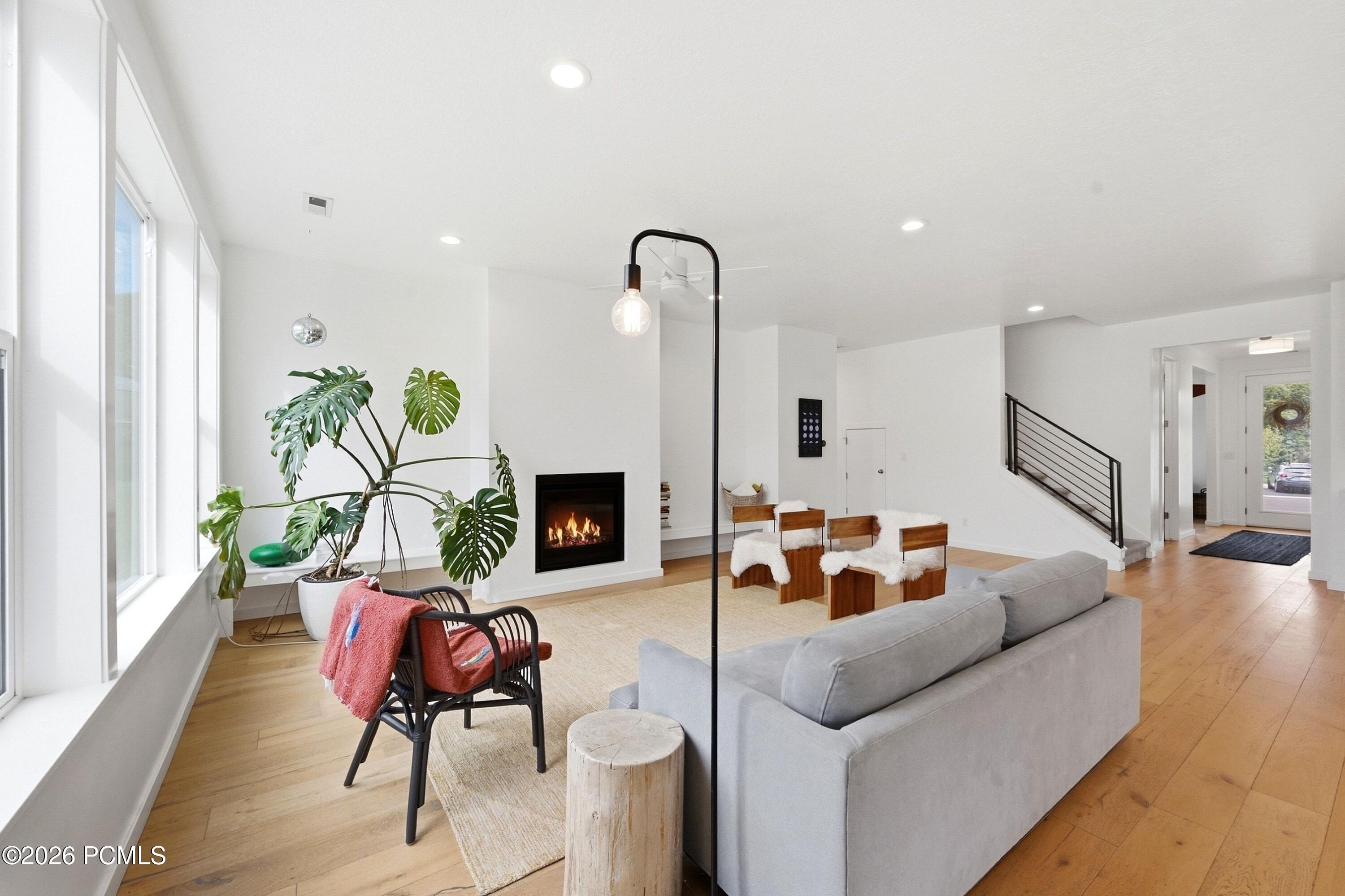 Living room with a modern fireplace, large windows, and a black-railed staircase.