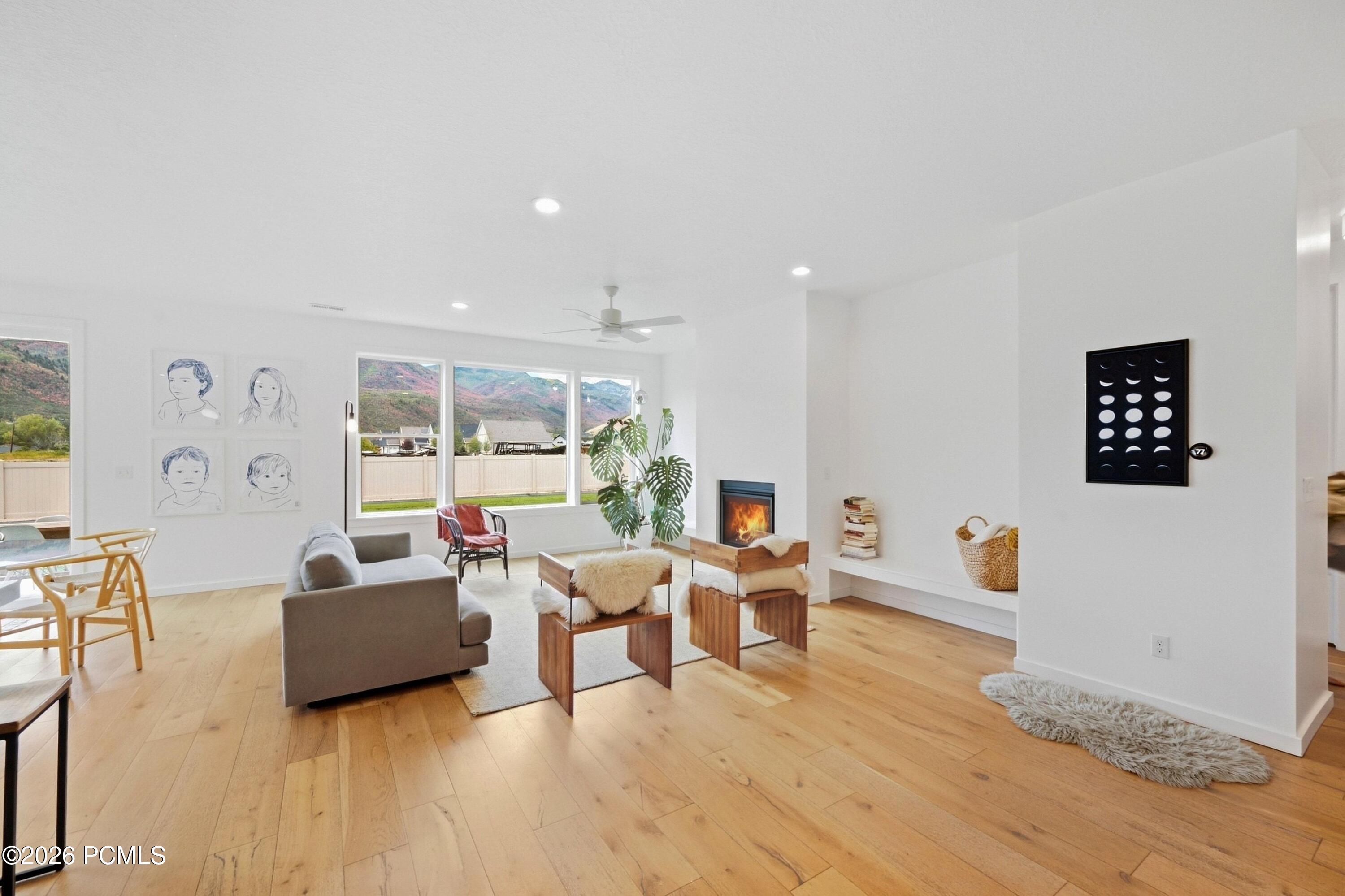 Furnished living room with a fireplace, wide mountain-view windows, and light wood floors.