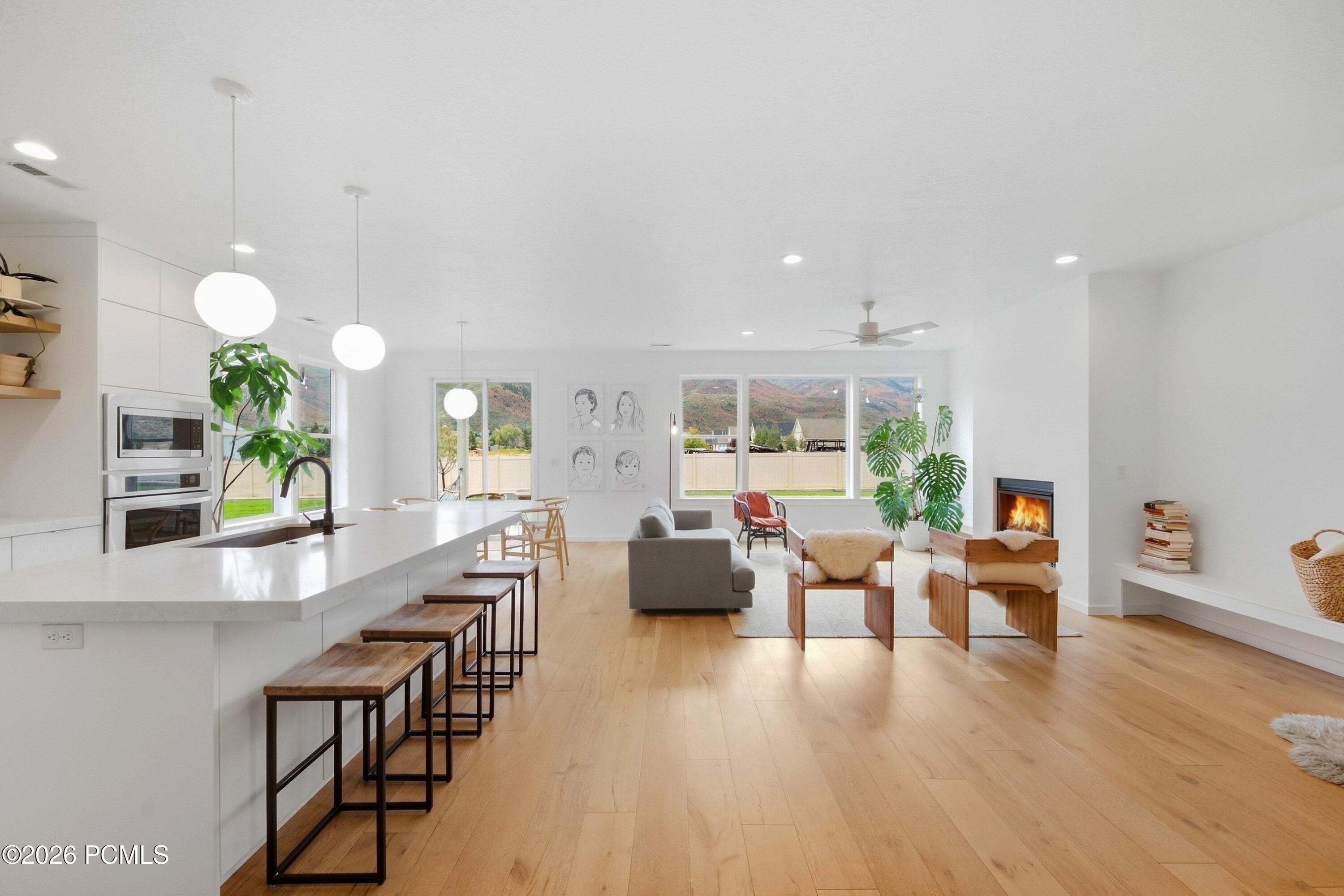 Open-plan kitchen and living room with a long island, fireplace, and mountain views through large windows.