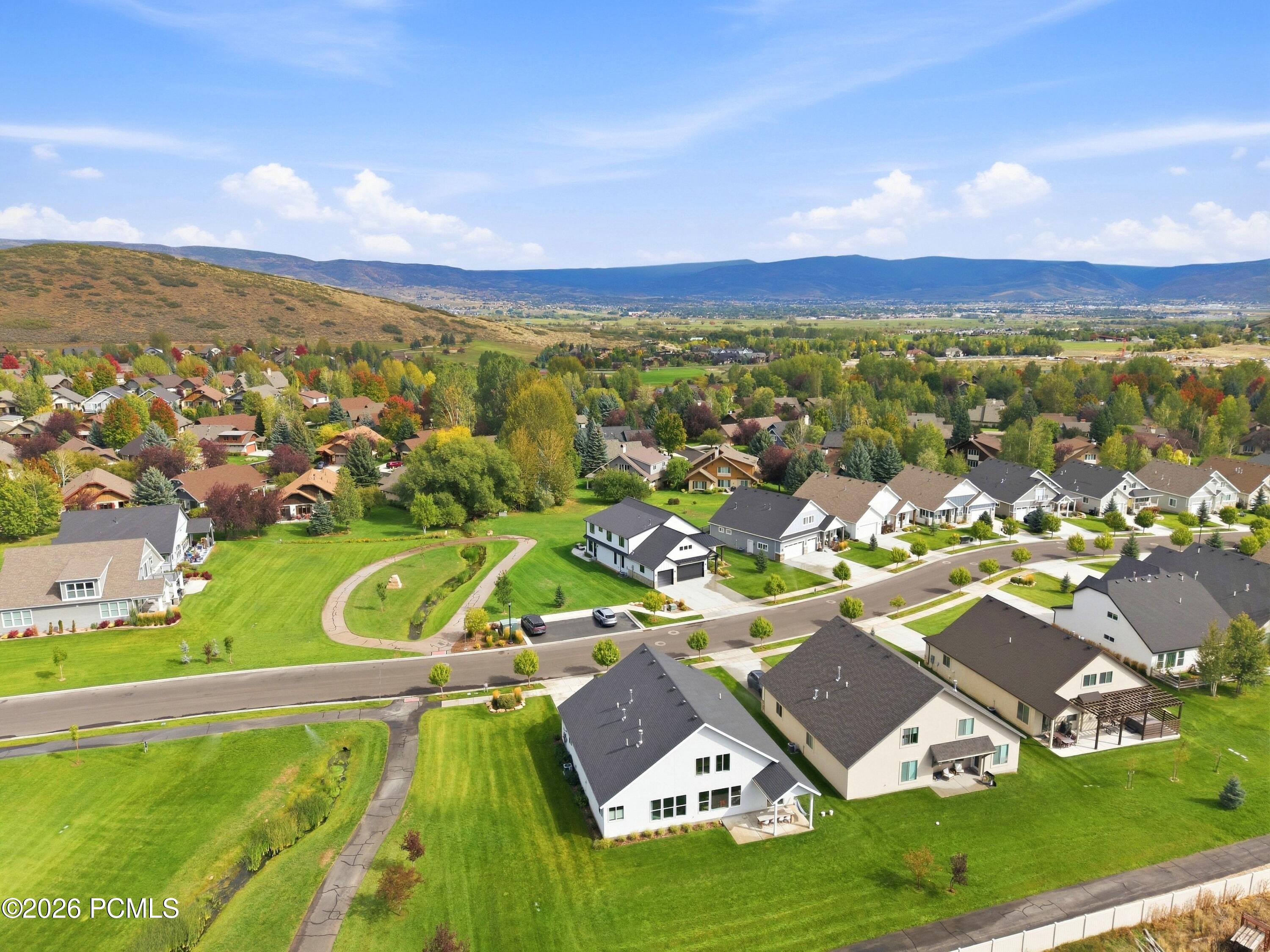 Aerial view of neighborhood homes and autumn trees, with mountain ridges across the valley beyond.