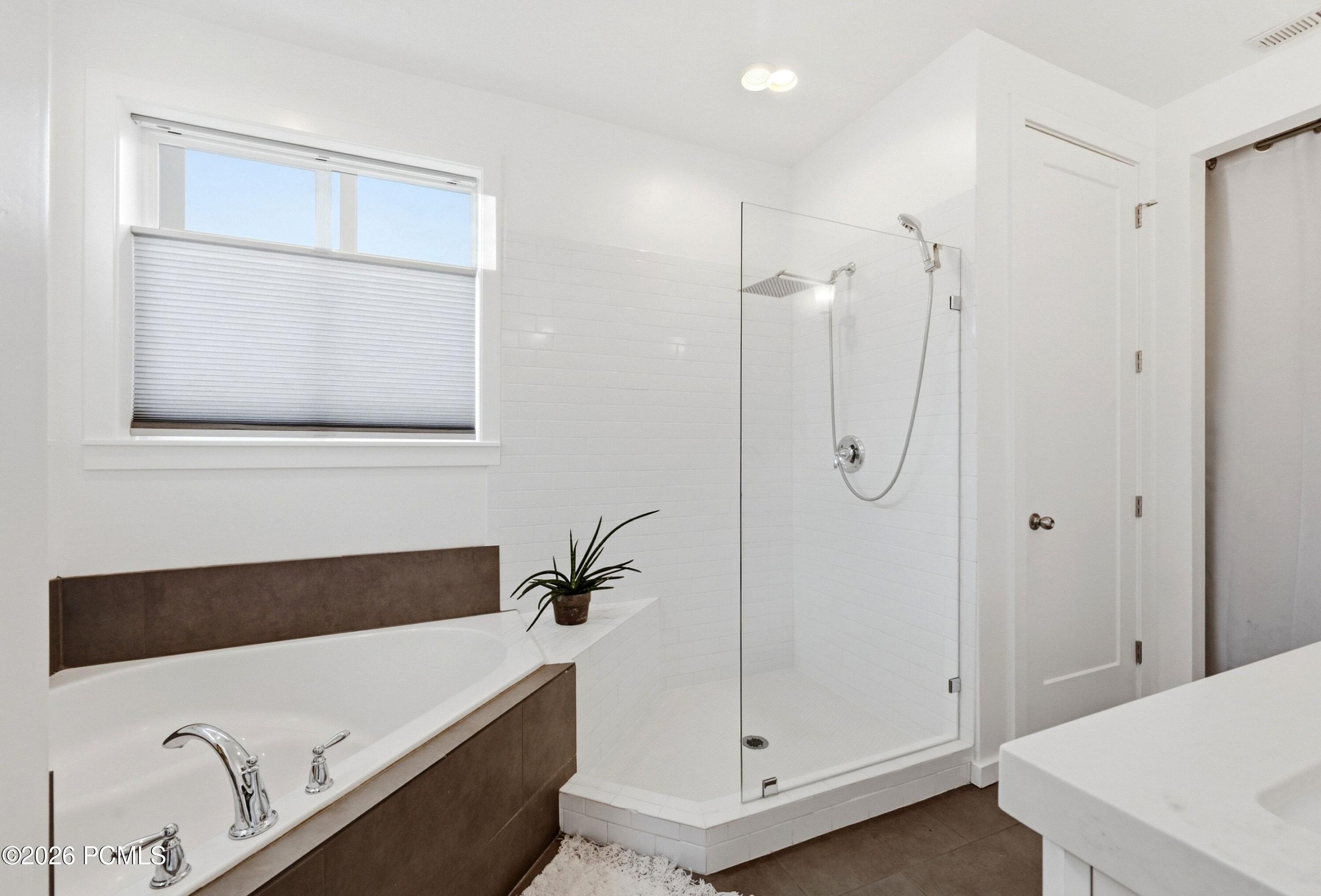 Bathroom with a built-in tub and glass-enclosed tiled shower.