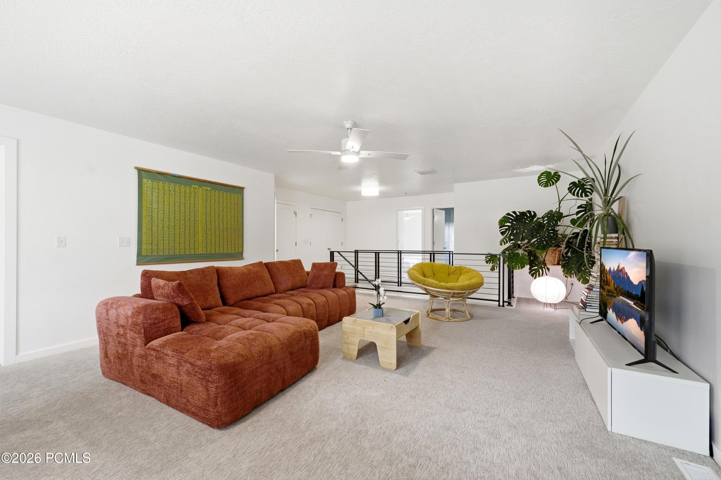 Upstairs living room with a rust-colored sectional, green papasan chair, and black metal railing.