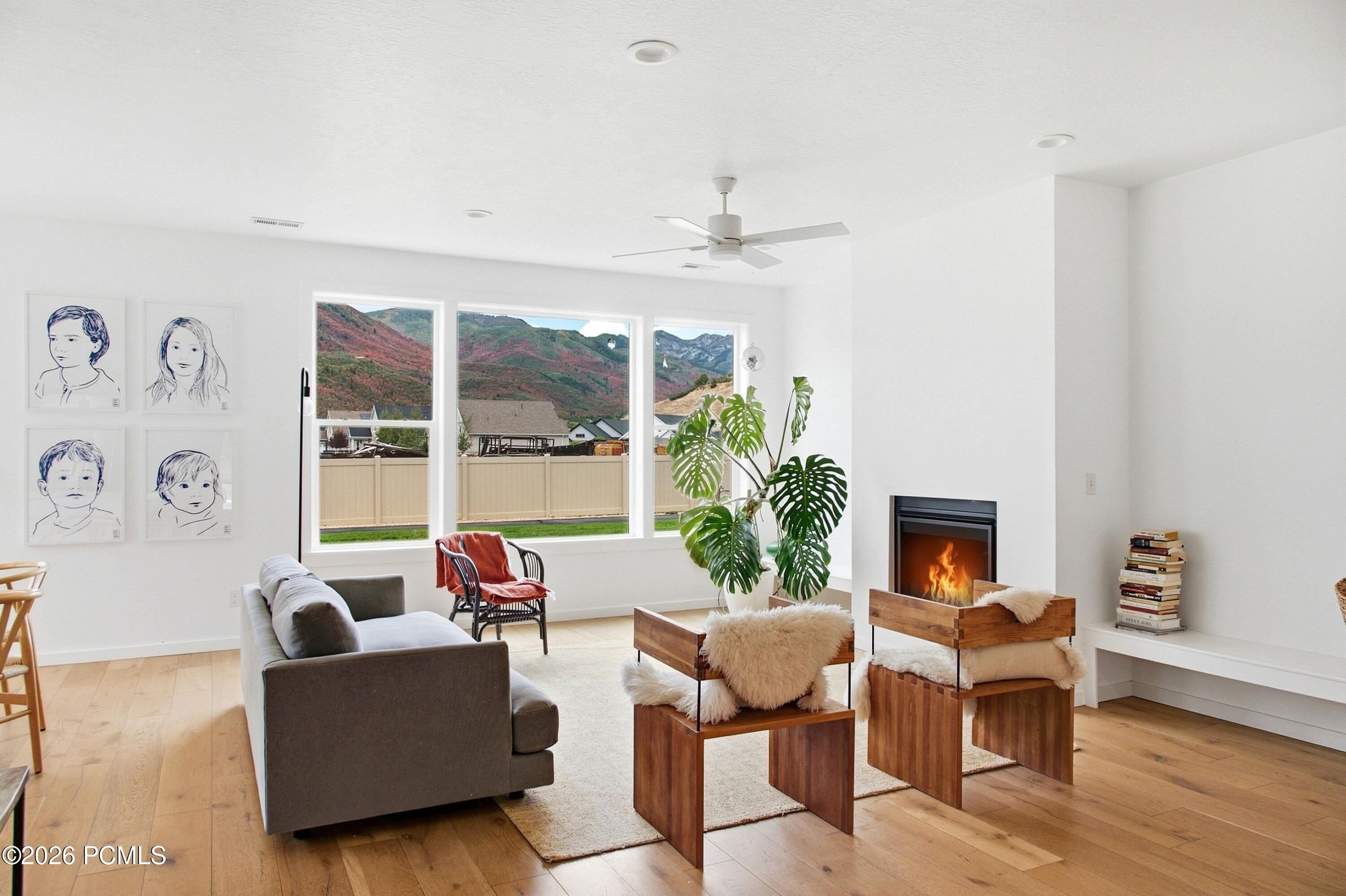Living room with a lit fireplace, large mountain-view windows, and warm wood floors.