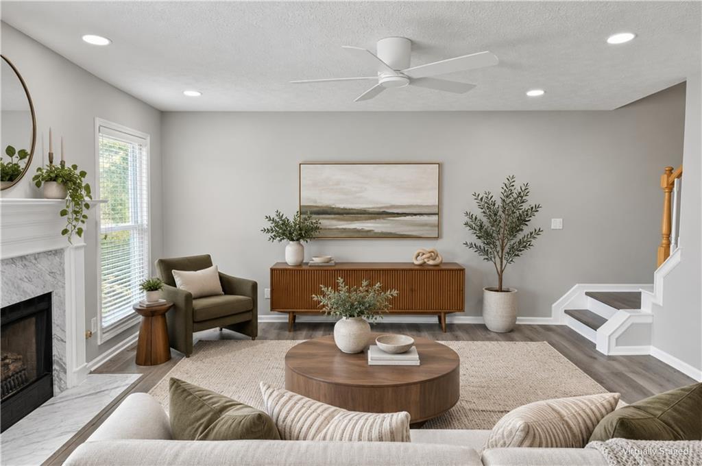 Staged living room with a white fireplace, round coffee table, and staircase.