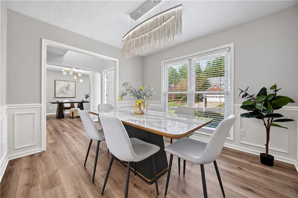 Dining room with a marble-look table, white chairs, and a modern linear chandelier.