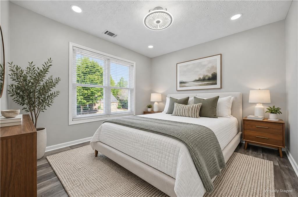 Virtually staged bedroom with a white bed, gray-green bedding, and a large window with blinds.