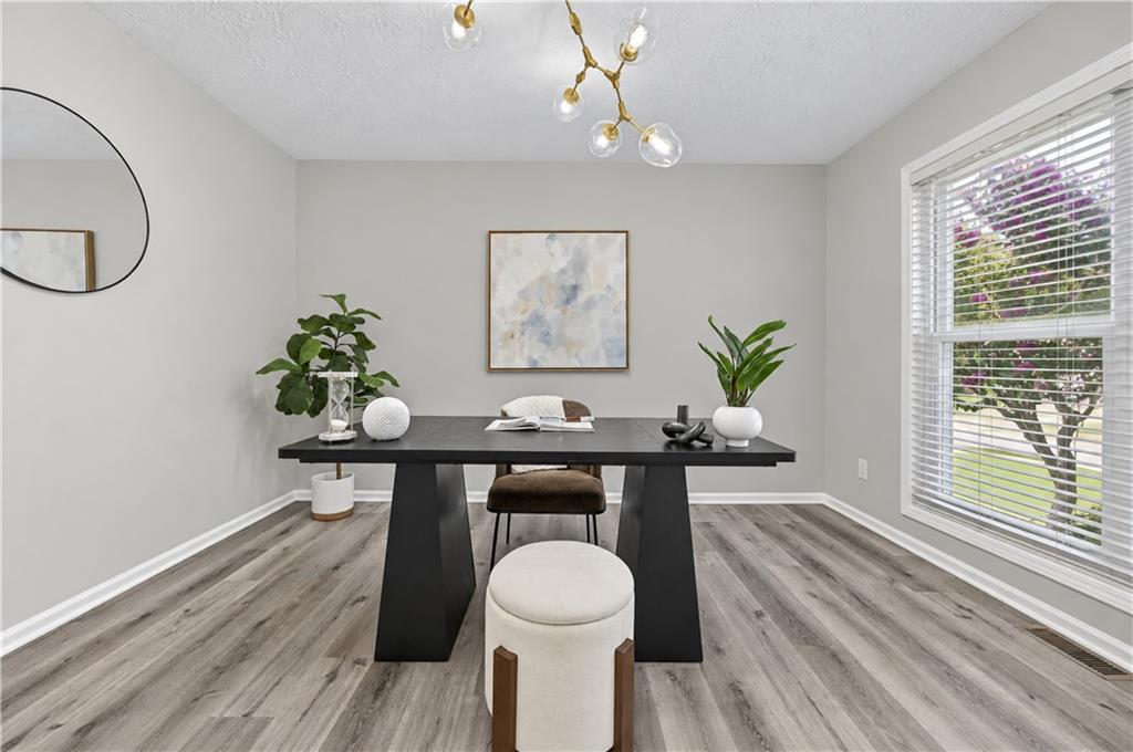 Staged dining room with a dark table, sculptural chandelier, and large window overlooking greenery.