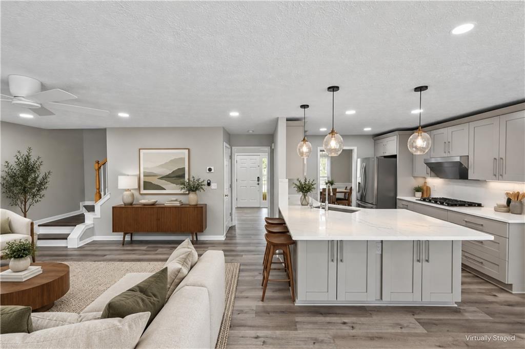 Open-plan kitchen and living area with a large island, pendant lights, and gray cabinetry.
