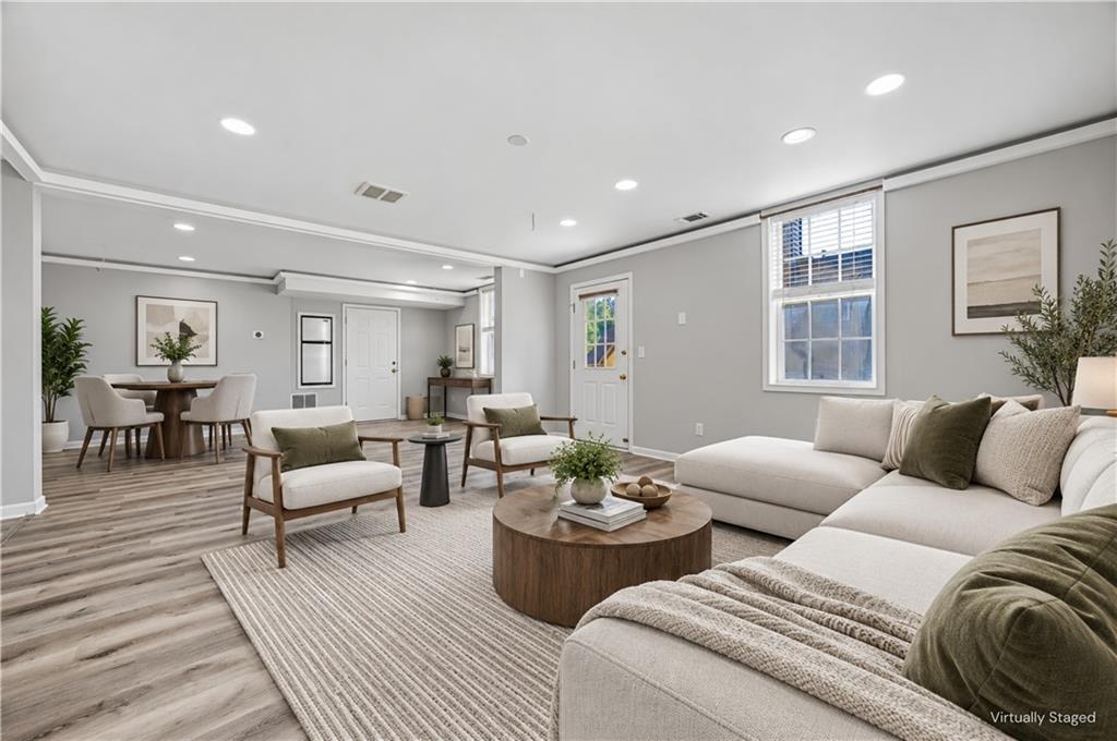 Open-plan living and dining room with a large sectional sofa and light wood-look flooring.