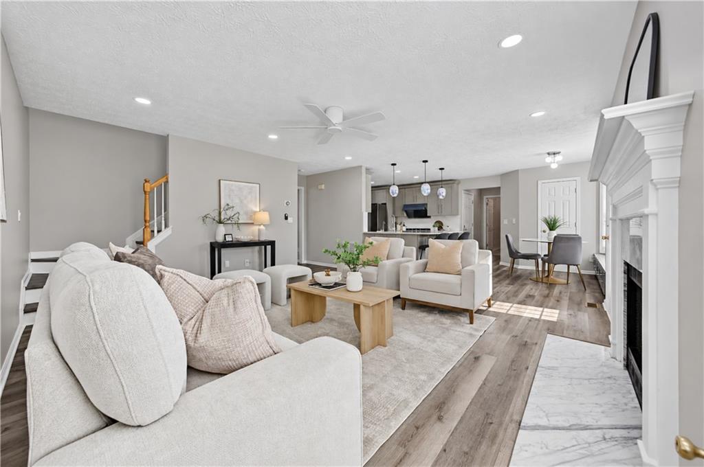 Open-plan living room with a white sectional, fireplace, and kitchen and dining area beyond.