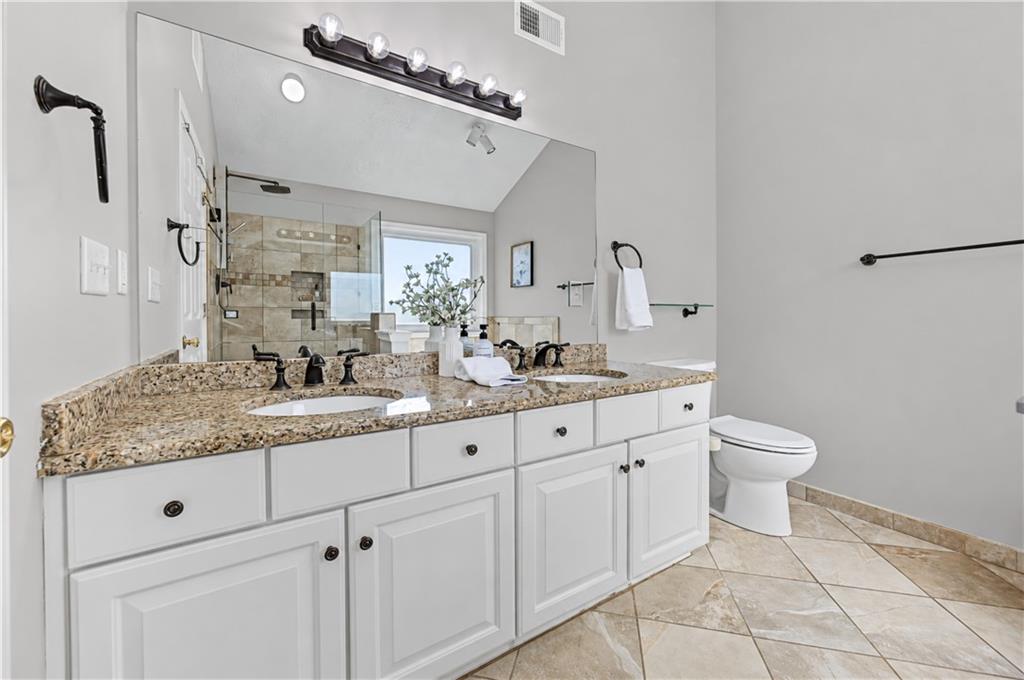 Bathroom with a double-sink granite vanity and tiled walk-in shower.