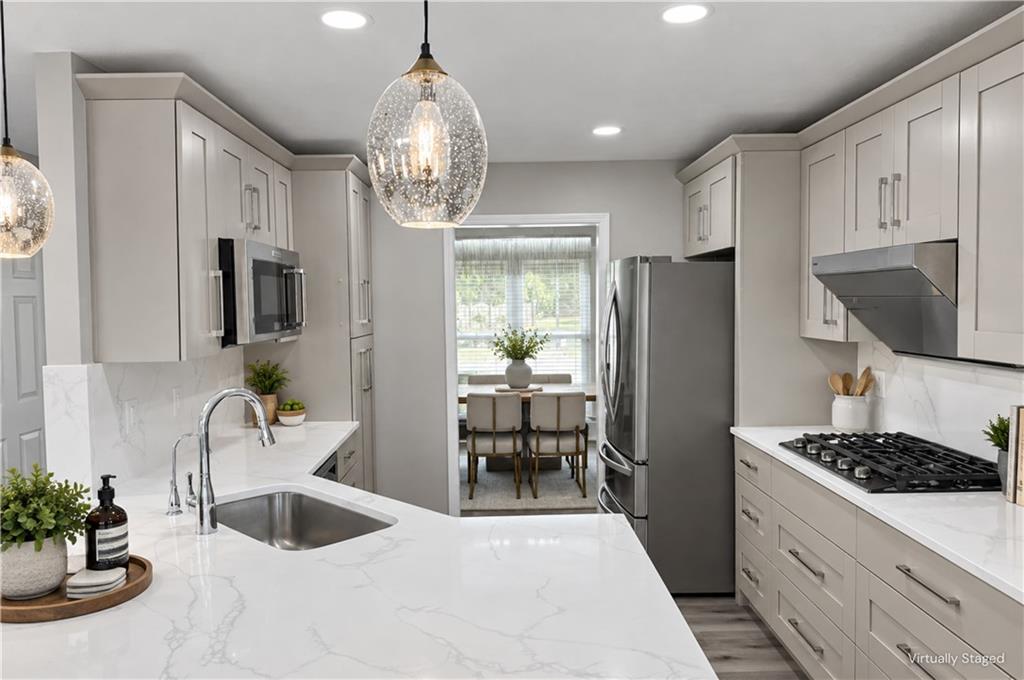 Modern kitchen with a white island, stainless steel appliances, and a dining nook by the window.