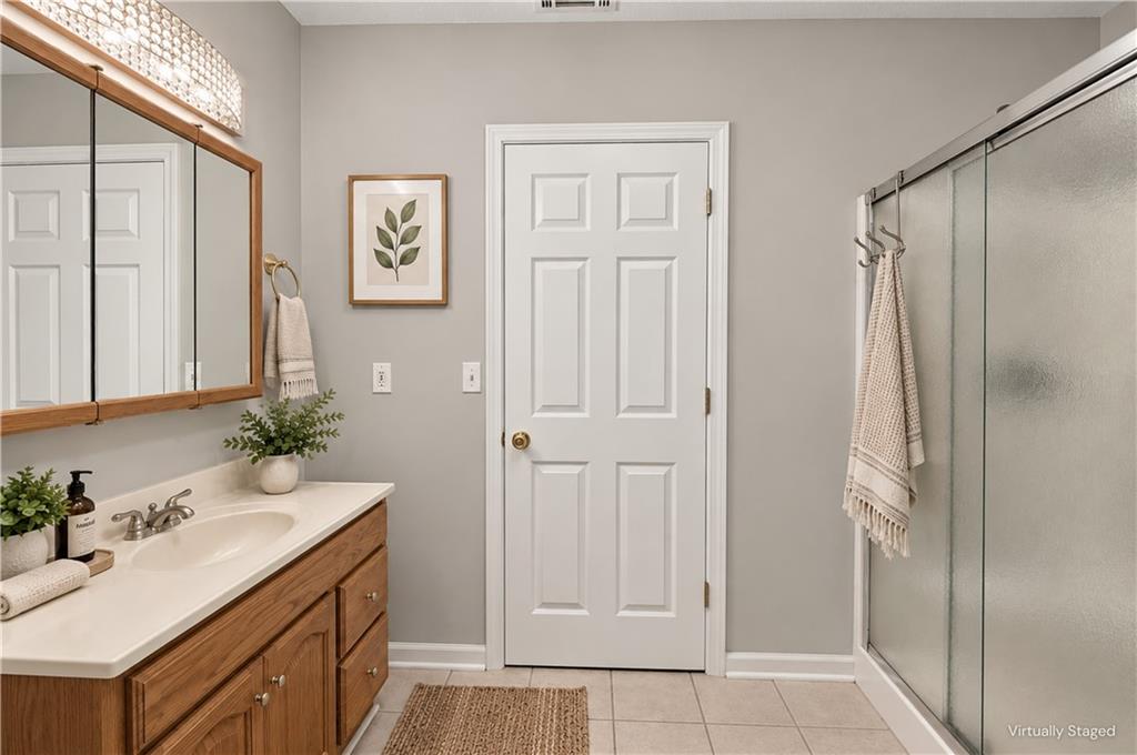 Bathroom with a wood vanity, mirrored cabinet, and glass-enclosed shower.