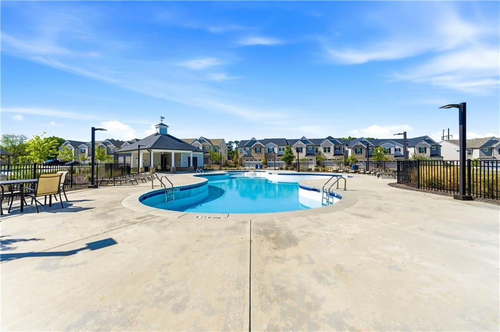 Community swimming pool with curved blue water, a cabana, and surrounding homes.