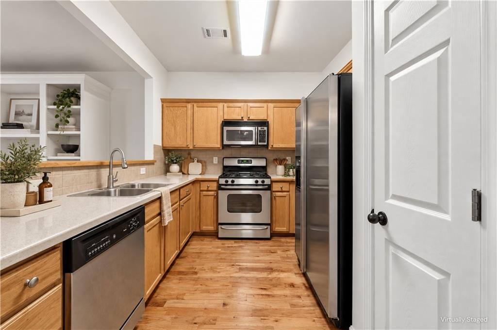 Kitchen with honey-colored cabinets, hardwood floors, and stainless steel appliances.