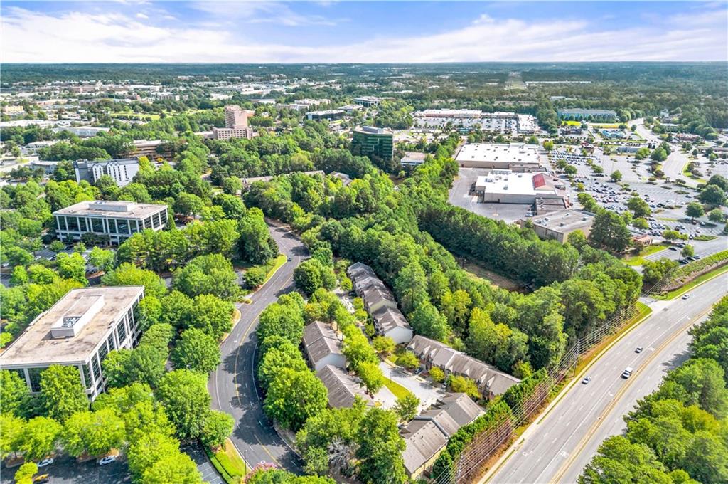 Aerial view of attached homes among trees, office buildings, and a busy road.