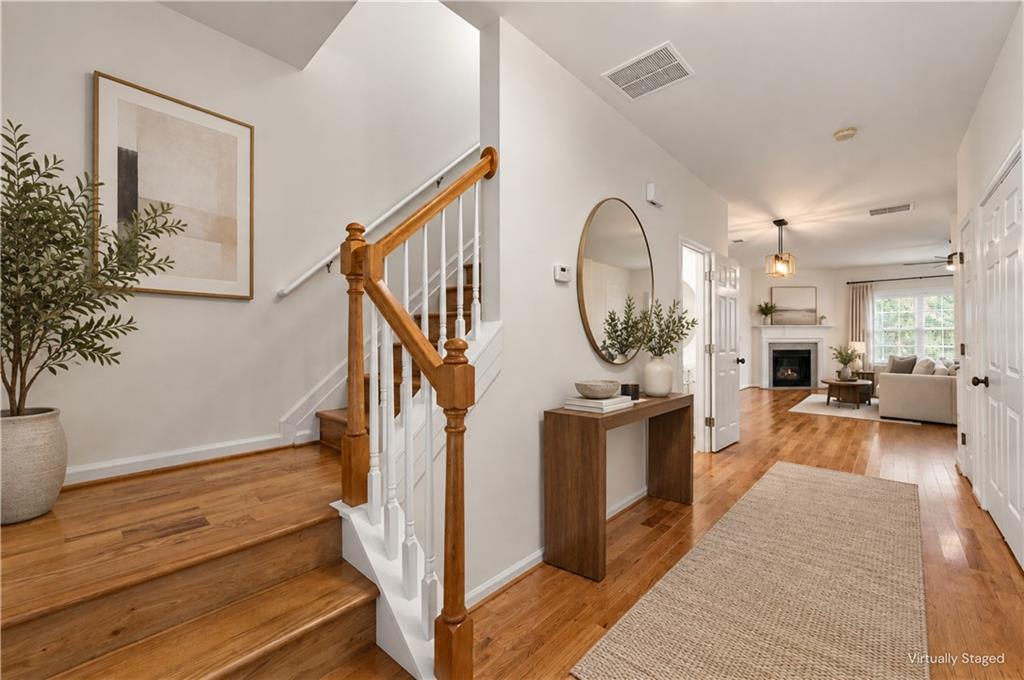 Entryway with hardwood floors, a wood-and-white staircase, and a console table beside the living room.
