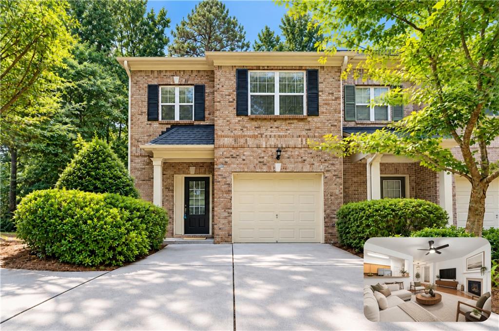 Two-story brick home with black shutters, attached garage, and landscaped front yard.