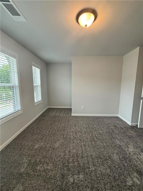 Empty carpeted room with two windows and a ceiling light.