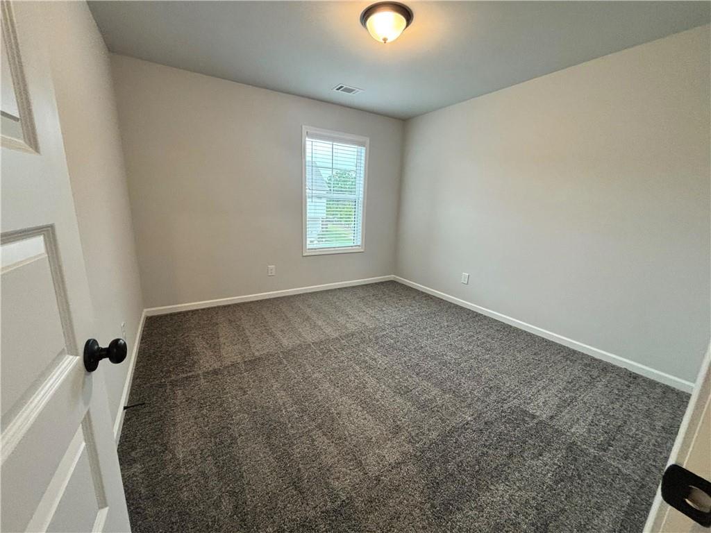 Empty carpeted bedroom with a single window and white blinds.