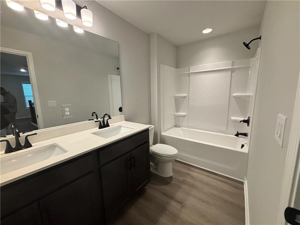 Bathroom with a dark double vanity, toilet, and white tub-shower surround.