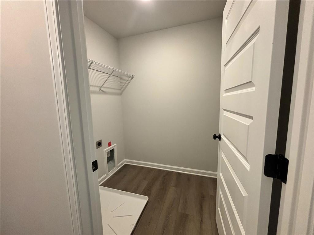 Laundry room with a wire shelf, wood-look flooring, and a small pet door.