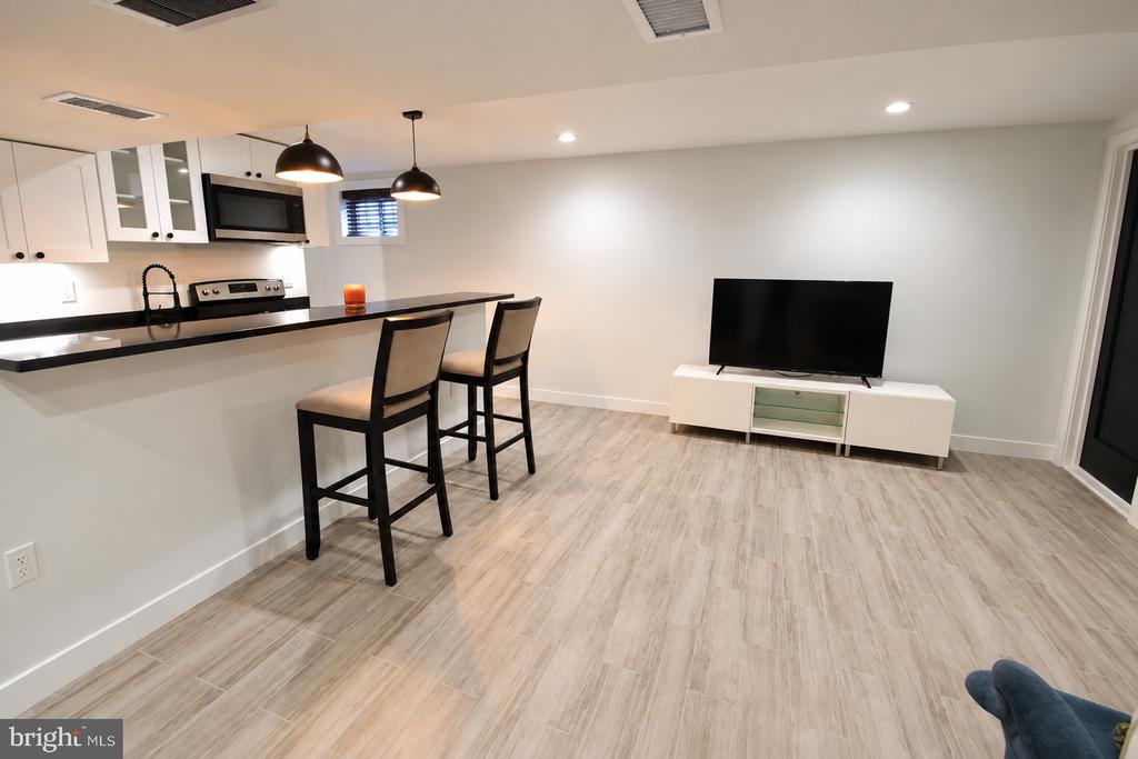 Kitchen and living area with a breakfast bar, two tall chairs, and a television.