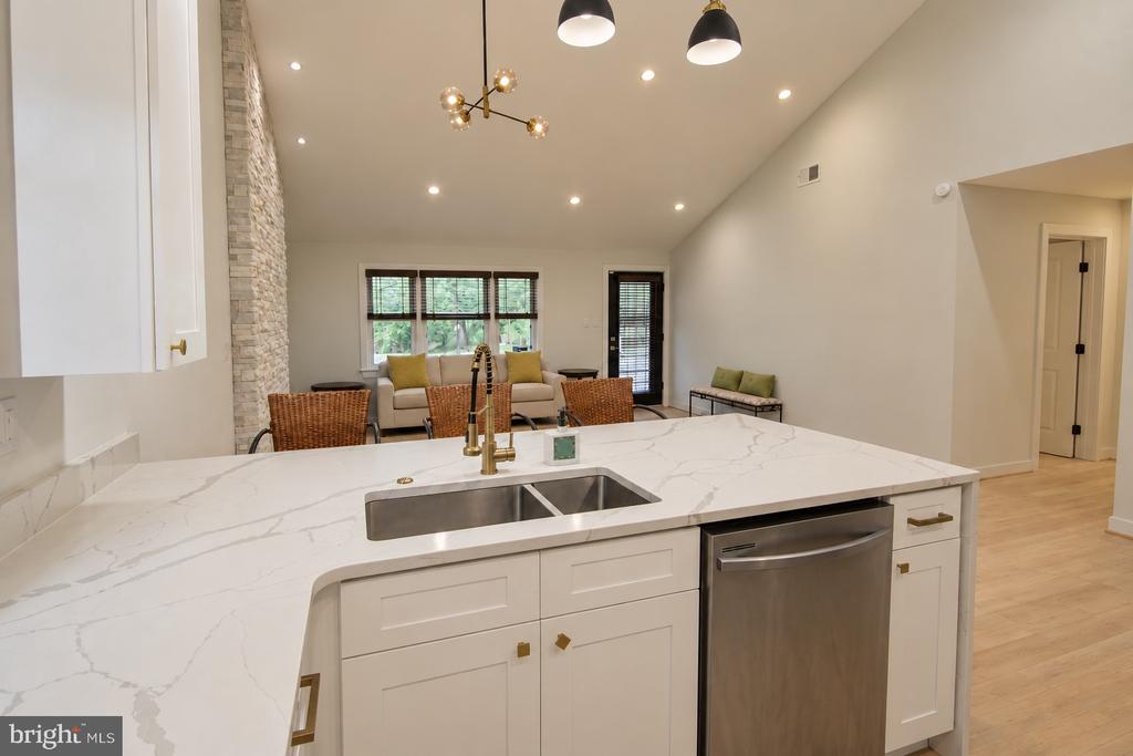 Modern kitchen island with a white veined countertop and sink, opening onto a furnished living room.
