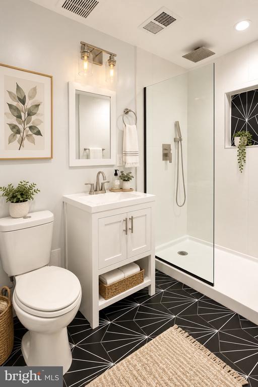 Bathroom with a white vanity and glass shower, black geometric tile, and botanical artwork.