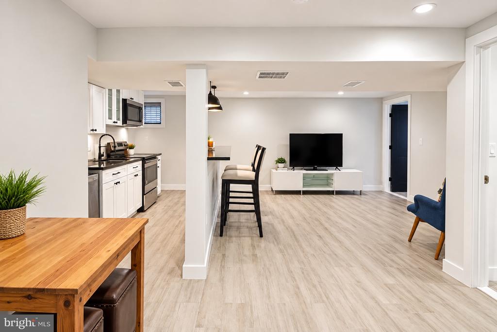 Open-plan living area with a compact white kitchen, breakfast bar, and TV.