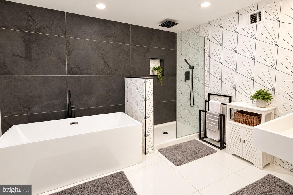 Modern bathroom with a freestanding tub, glass shower, dark tile, and geometric patterned walls.