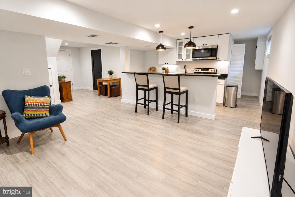Open-plan living room and kitchen with a white island, bar stools, and blue accent chair.