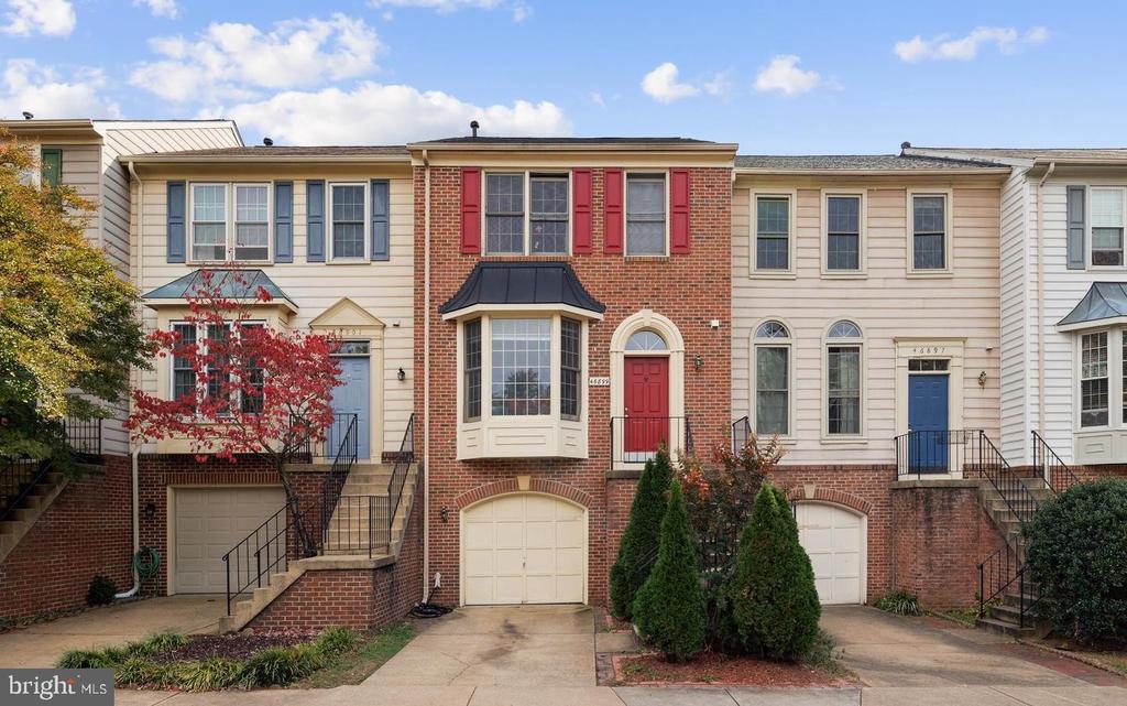 Brick townhouse with a red front door, bay window, and attached garage.