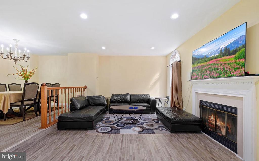 Living room with a black leather sectional, patterned rug, and fireplace.