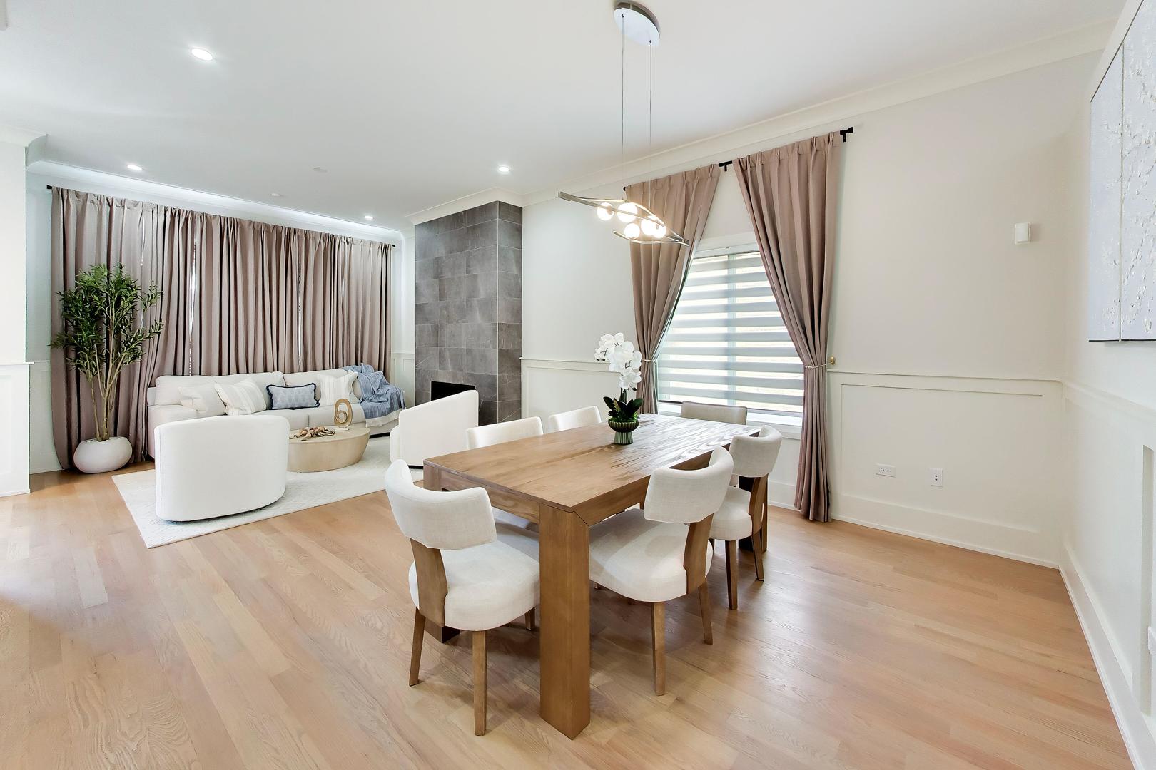 Living and dining area with a gray tiled fireplace, white sofa, and wooden dining table.