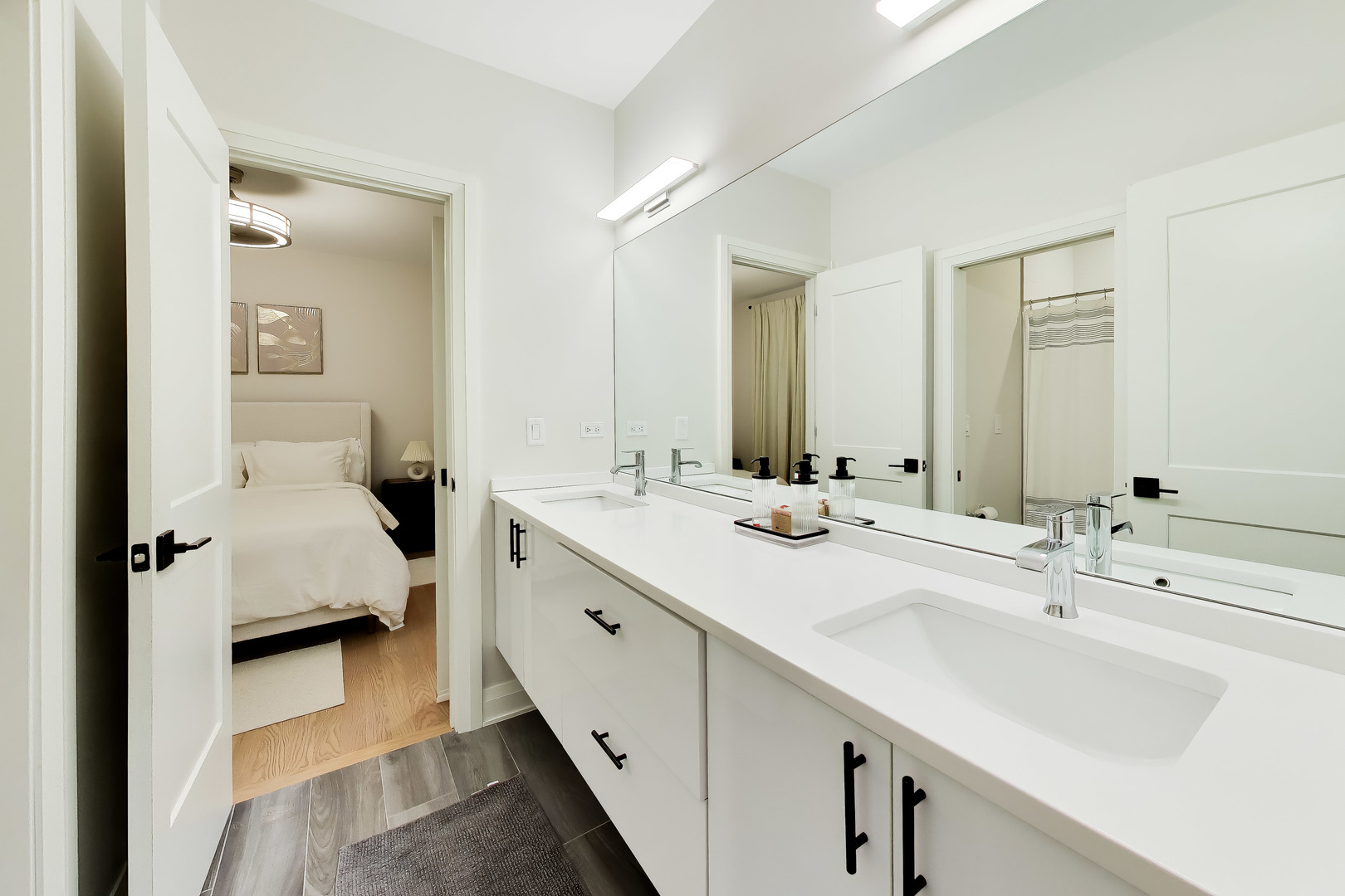Bathroom with a double-sink vanity and a view into an adjoining bedroom.