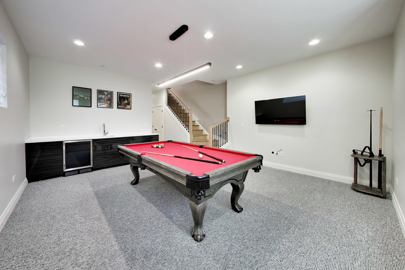 Recreation room with a red pool table, built-in wet bar, and staircase.